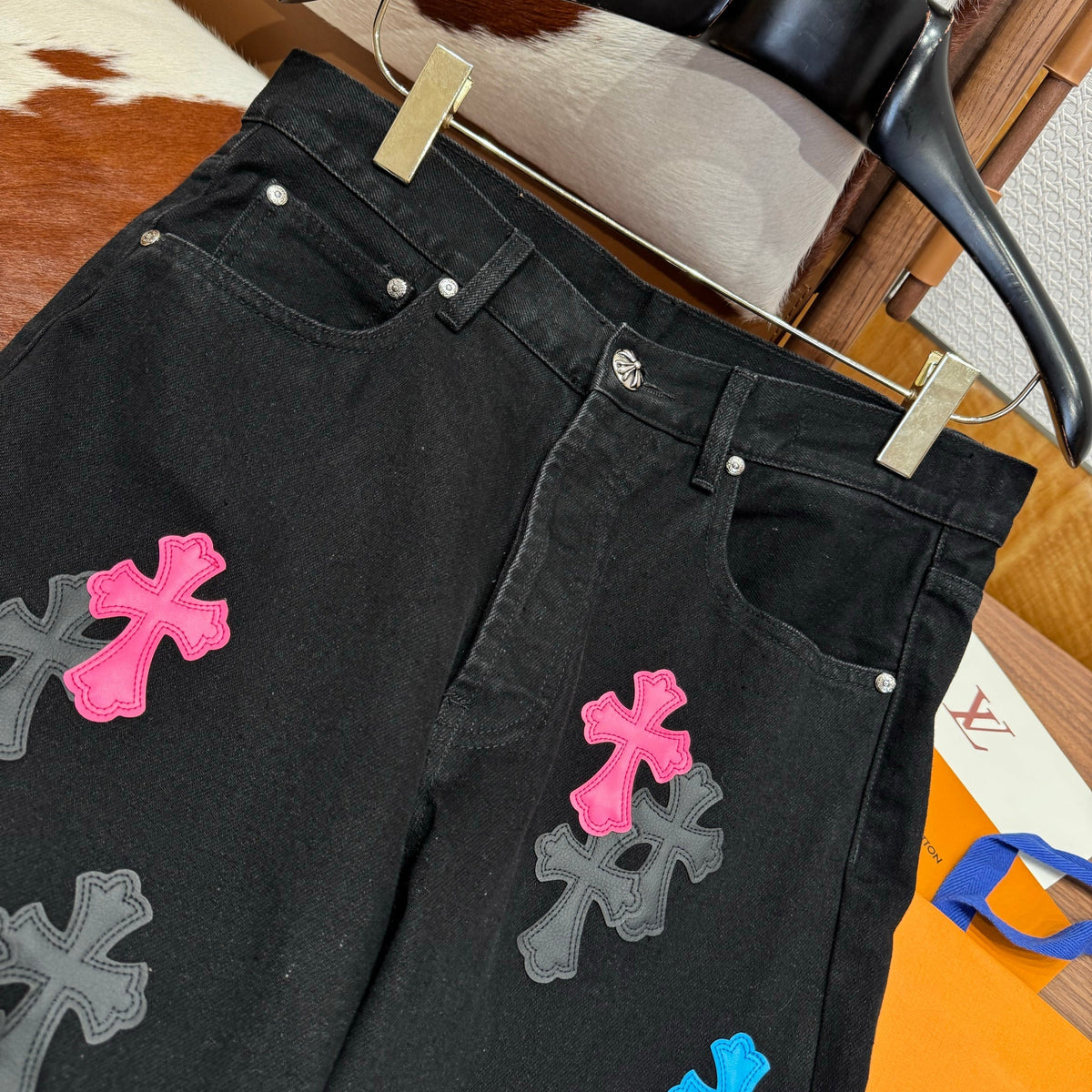 Chrome Hearts Jeans flat lay on neutral background